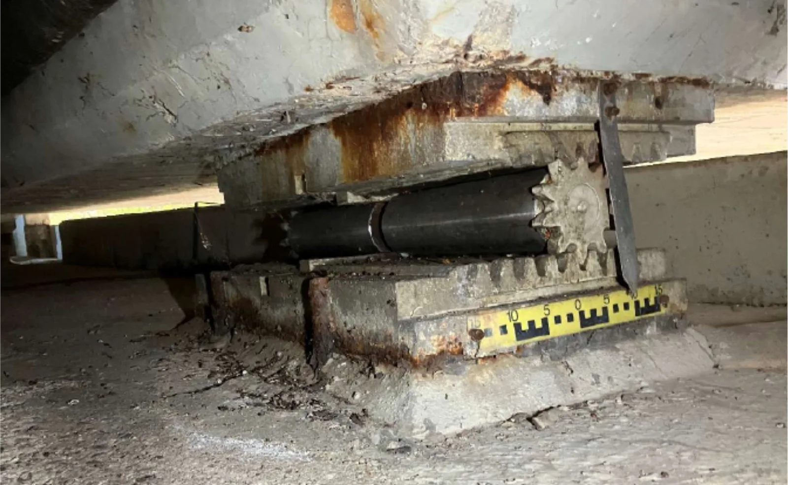 Rollenlager unter einem Brückenüberbau, daneben eine gelbe Messskala zur Ablesung des Lagerwegs