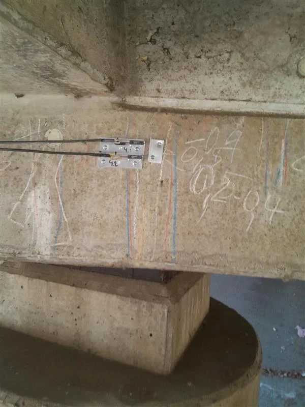 Two displacement transducers on a bridge girder, screwed over marked cracks