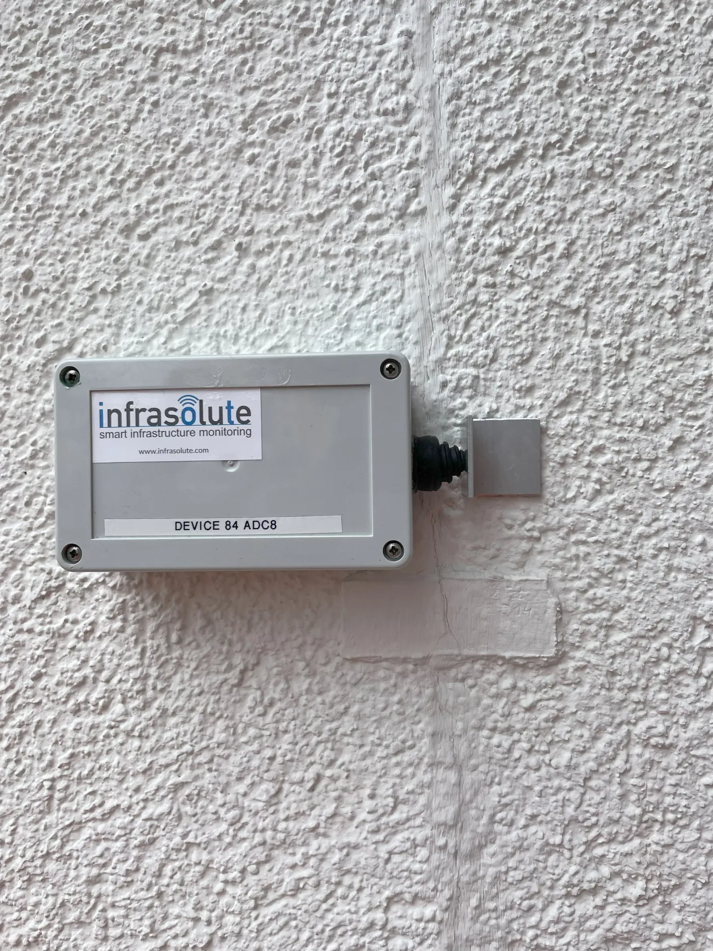 Risssensor an einer Putzfassade über einem Riss montiert, mit Wegaufnehmer auf der Gegenseite