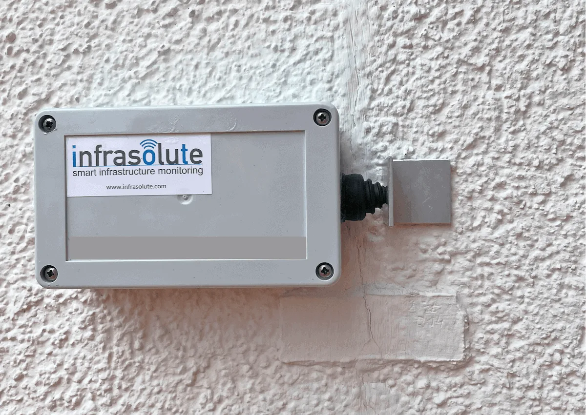 Risssensor mit Langzeitbatterie von Infrasolute, an einer Fassade über einem Riss montiert