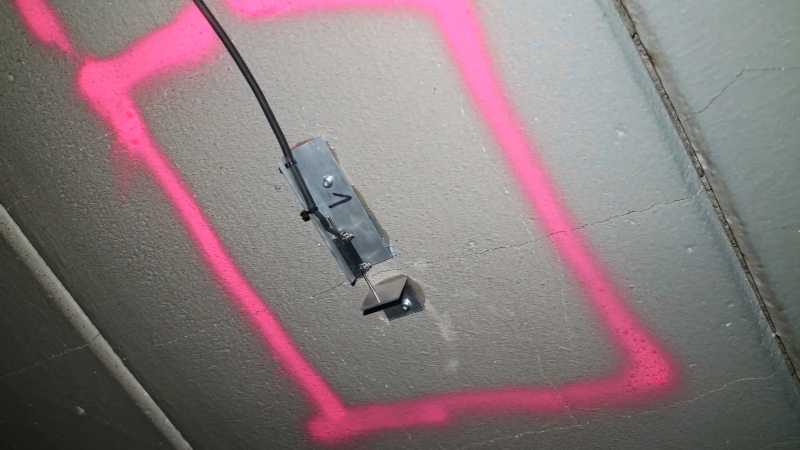 Risssensor an einem farbig markierten Riss in einer Betondecke
