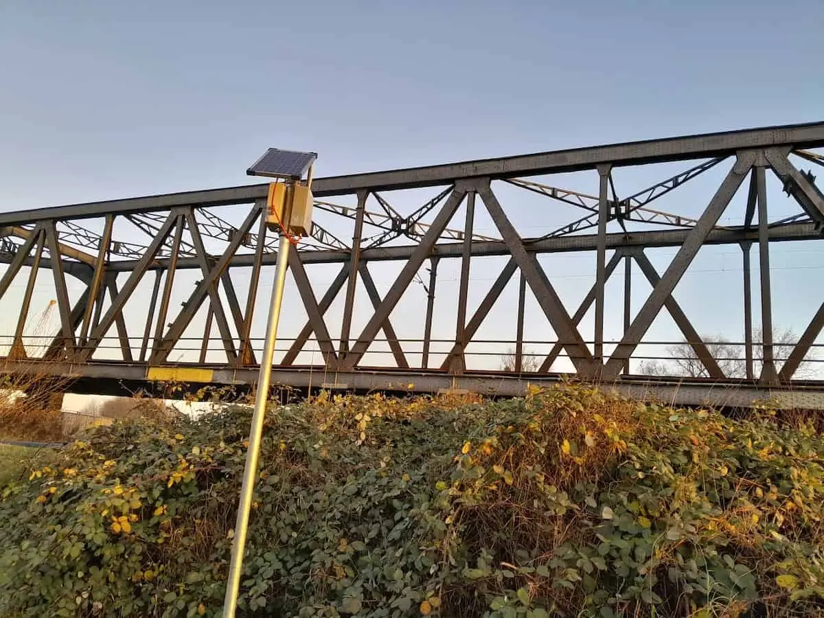 Solarversorgte Messeinheit neben einer Eisenbahnbrücke aus Stahlfachwerk